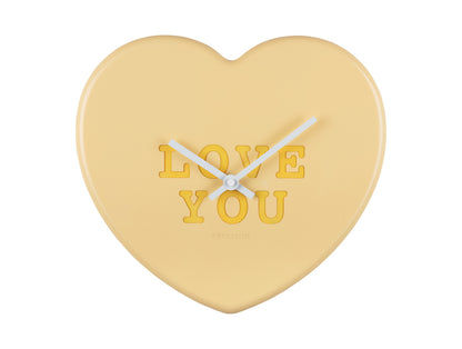 Hjärtformad väggklocka i ljusgult med texten "LOVE YOU" och visare