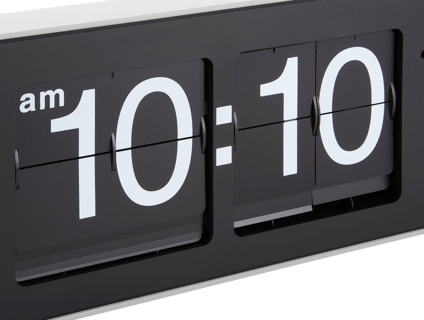Svart flipklocka på väggen i närbild med visning 10:10