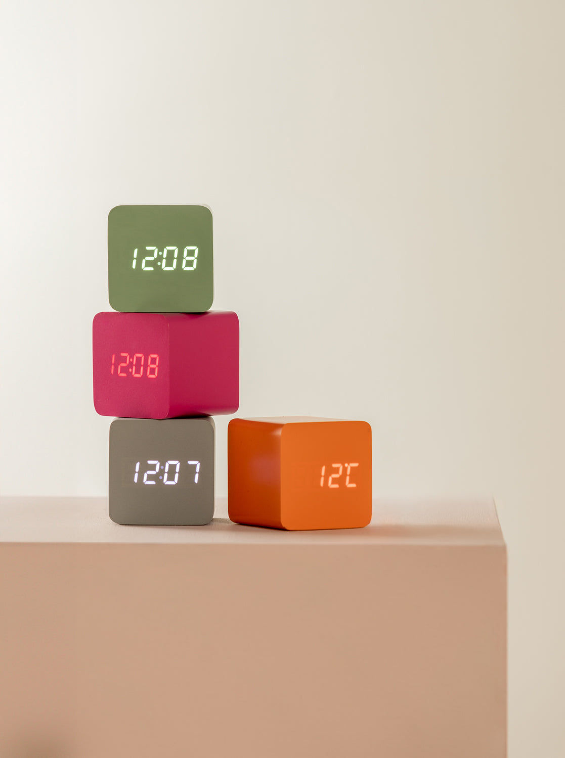 Fyra LED-väckarklockor i kubform i grönt, rosa, grått och orange med digital display
