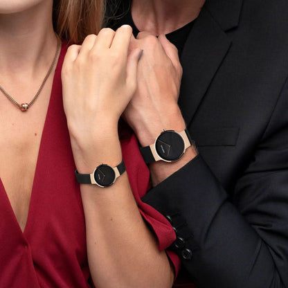 Två damklockor med svart urtavla, svart armband och boetter i roséguld