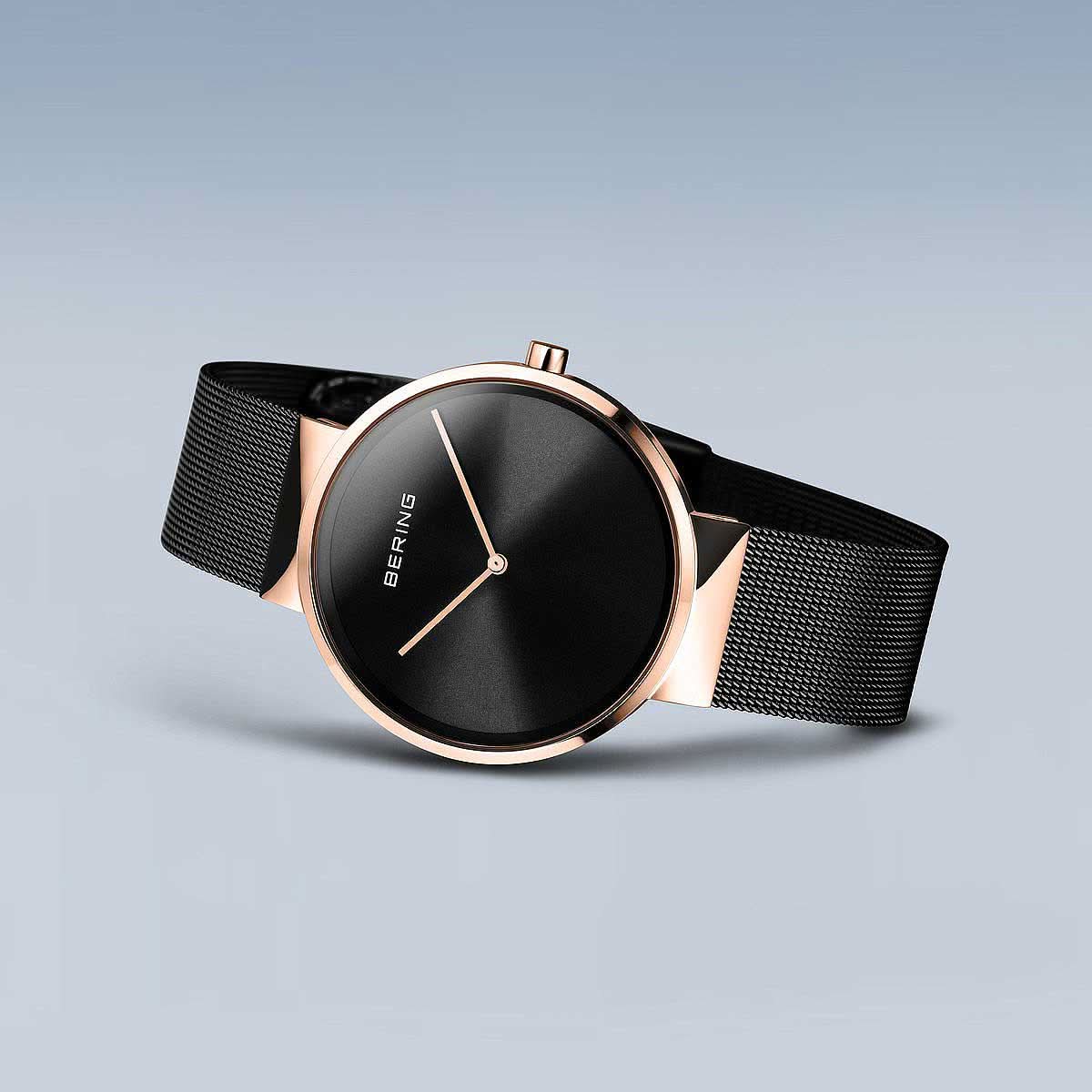 Klocka från sned vinkel med svart Milanese-armband och roséguldpläterad infattning