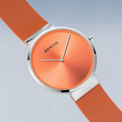 Analog klocka från sidan: orange urtavla och orange milanesearmband