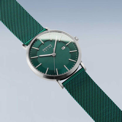 Herrklocka i sned vinkel: grön urtavla med index, silverfärgat hölje, mesh-armband