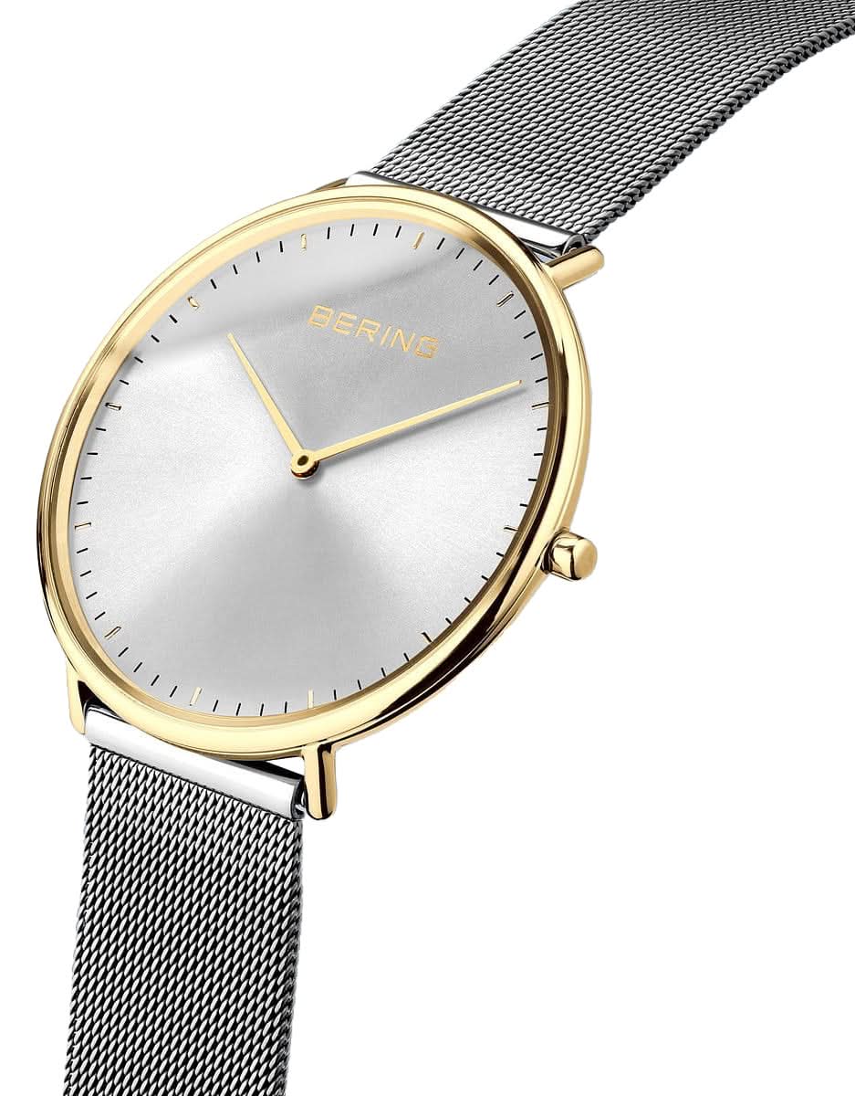 Herrklocka närbild: vit urtavla, guldfärgad kant och armband i silvermesh.