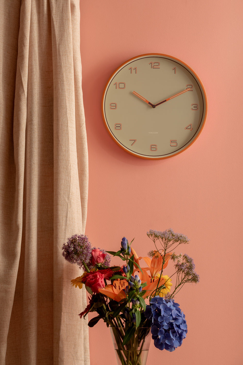 Rund väggklocka med orange ram, beige urtavla och orange visare