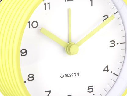 Väckarklocka i närbild: gul kant, vit urtavla, gröna visare och siffror