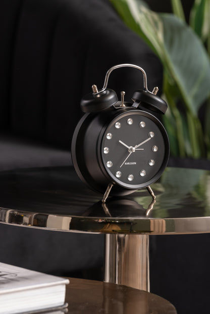 Karlsson klocka i svart med strass-siffror på metallhylla
