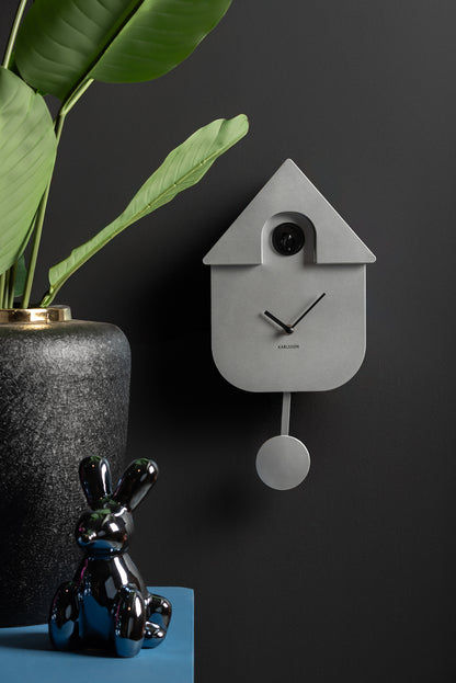 Modern väggklocka i husform, silverfärgat hölje med pendel