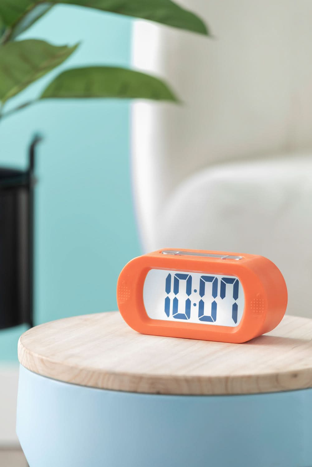 Orange digital väckarklocka med LCD-display 00:04 på träfot