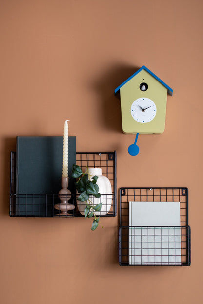 Väggklocka i husdesign, ljusgul med blått tak och rund urtavla