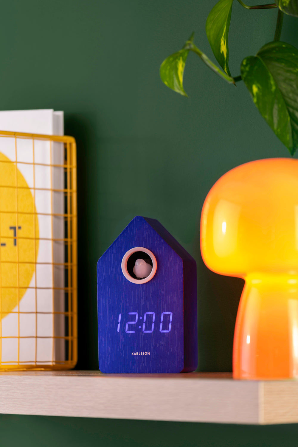 Karlsson LED-väckarklocka i gökhusdesign, blått hölje på hylla, med LED-display