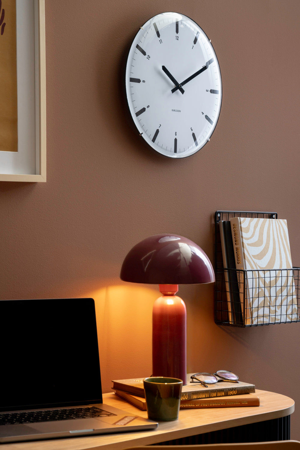 Rund väggklocka med vit urtavla och svarta visare på väggen