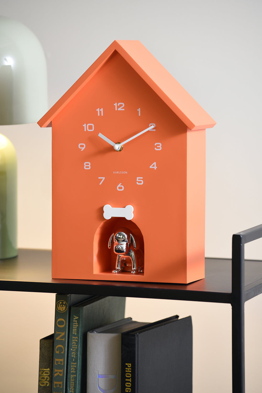 Orange väggklocka i hundkojeform med urverksfigur nedtill