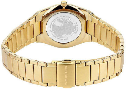 Baksidan på gyllene damklocka med graverat lock och metallarmband
