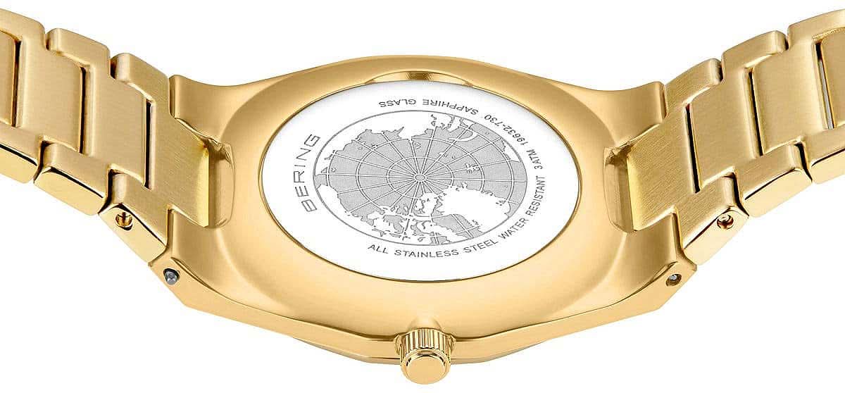 Baksida med graverat världskarta på ett gyllene metallarmband