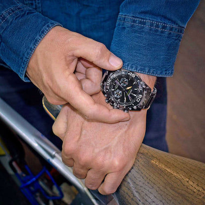 Kronografklocka för herrar i handen med svart urtavla och kamouflagemönstrat armband.