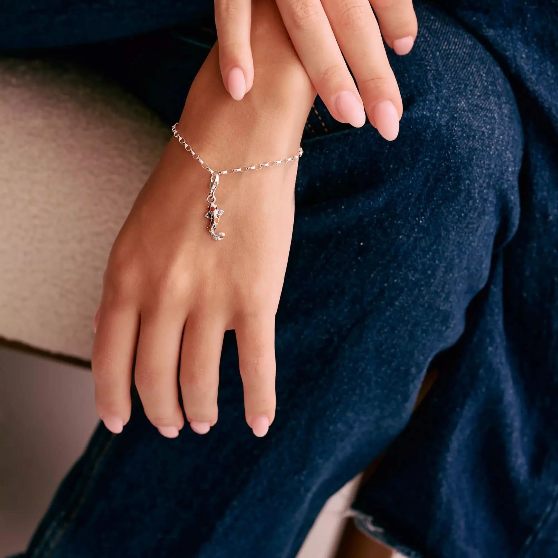 Koi-berlock på silverarmband runt handleden, silverögla med röda accenter