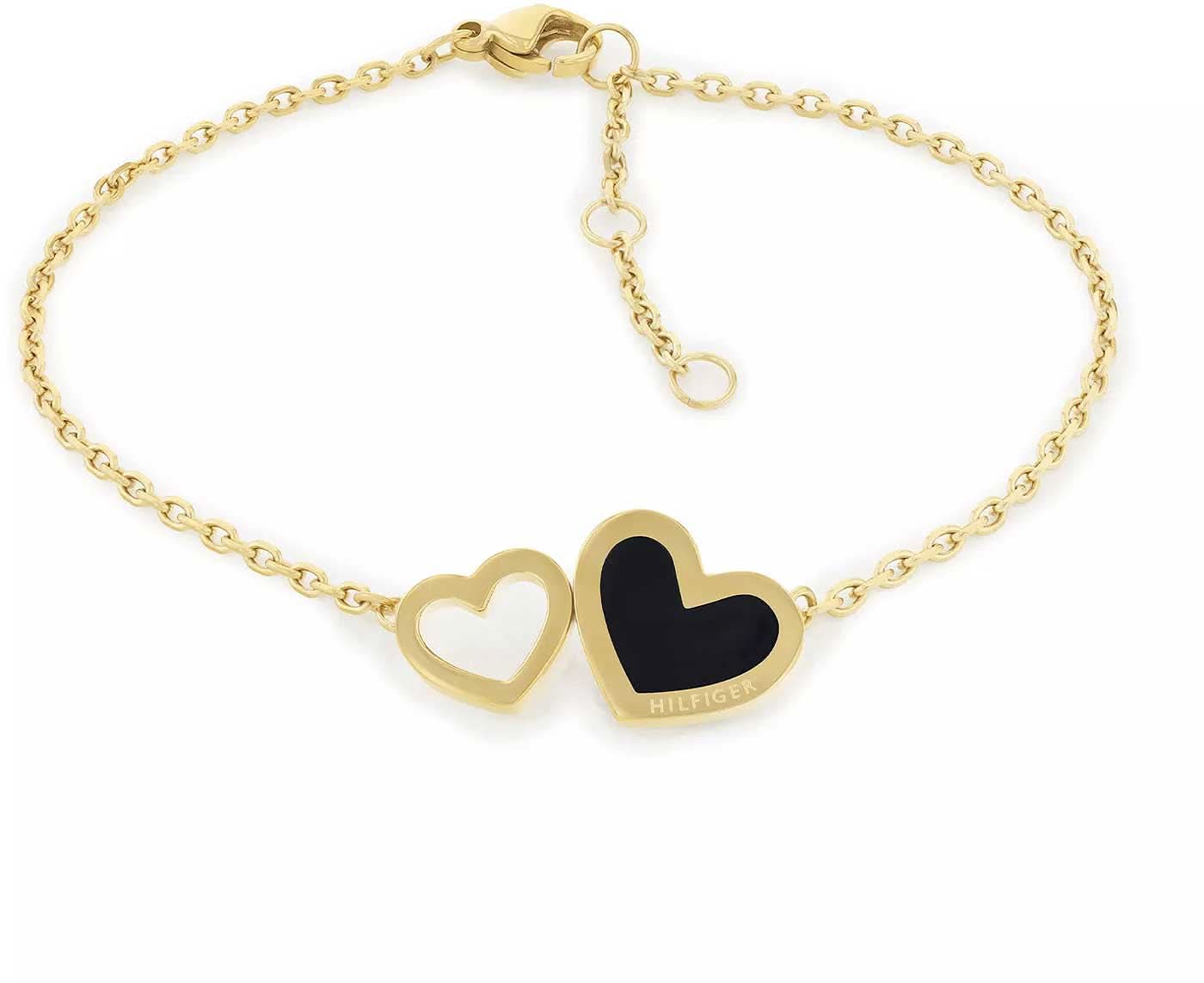 Guld-armband med två hjärtformade hängen, svart hjärta med Hilfiger-logotyp.