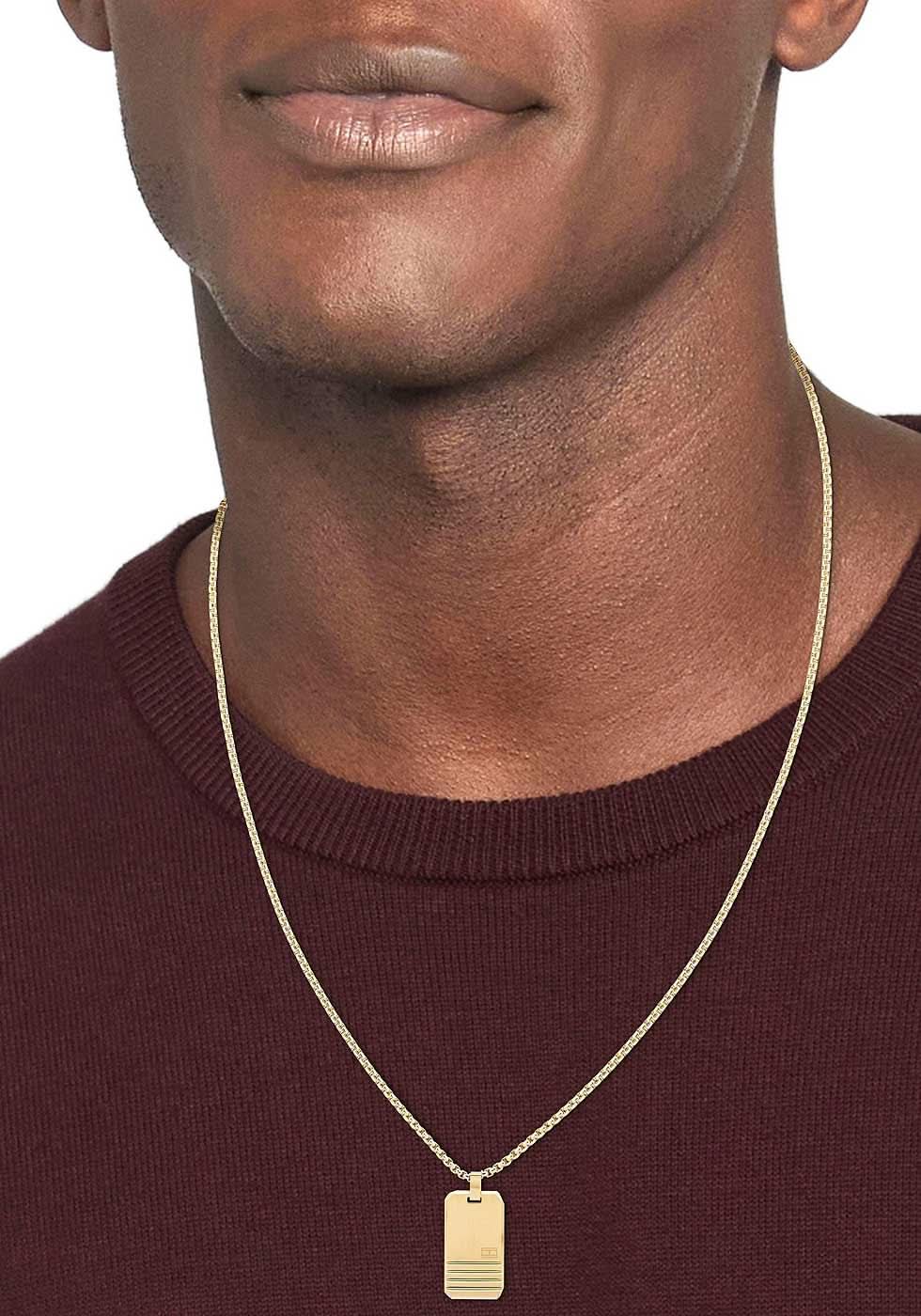 Gyllene halsband med rektangulärt hänge runt en modells hals