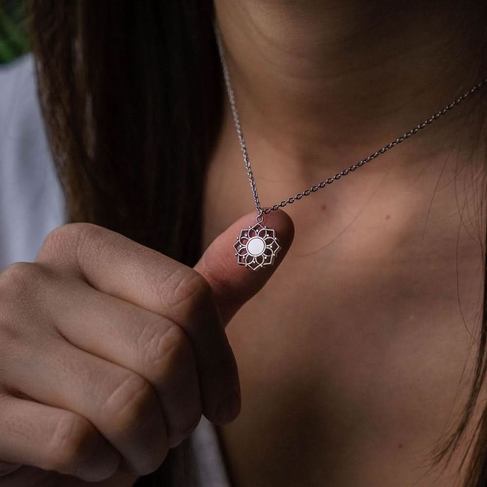 Halsband vid urringning med runt pärlemorhänge i solhjul, silverfärgad