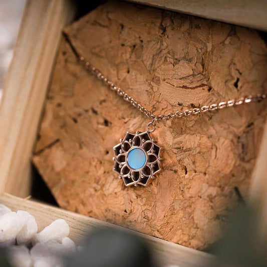 Halsband med runt hänge i blå pärlemor i en blomformad metallram