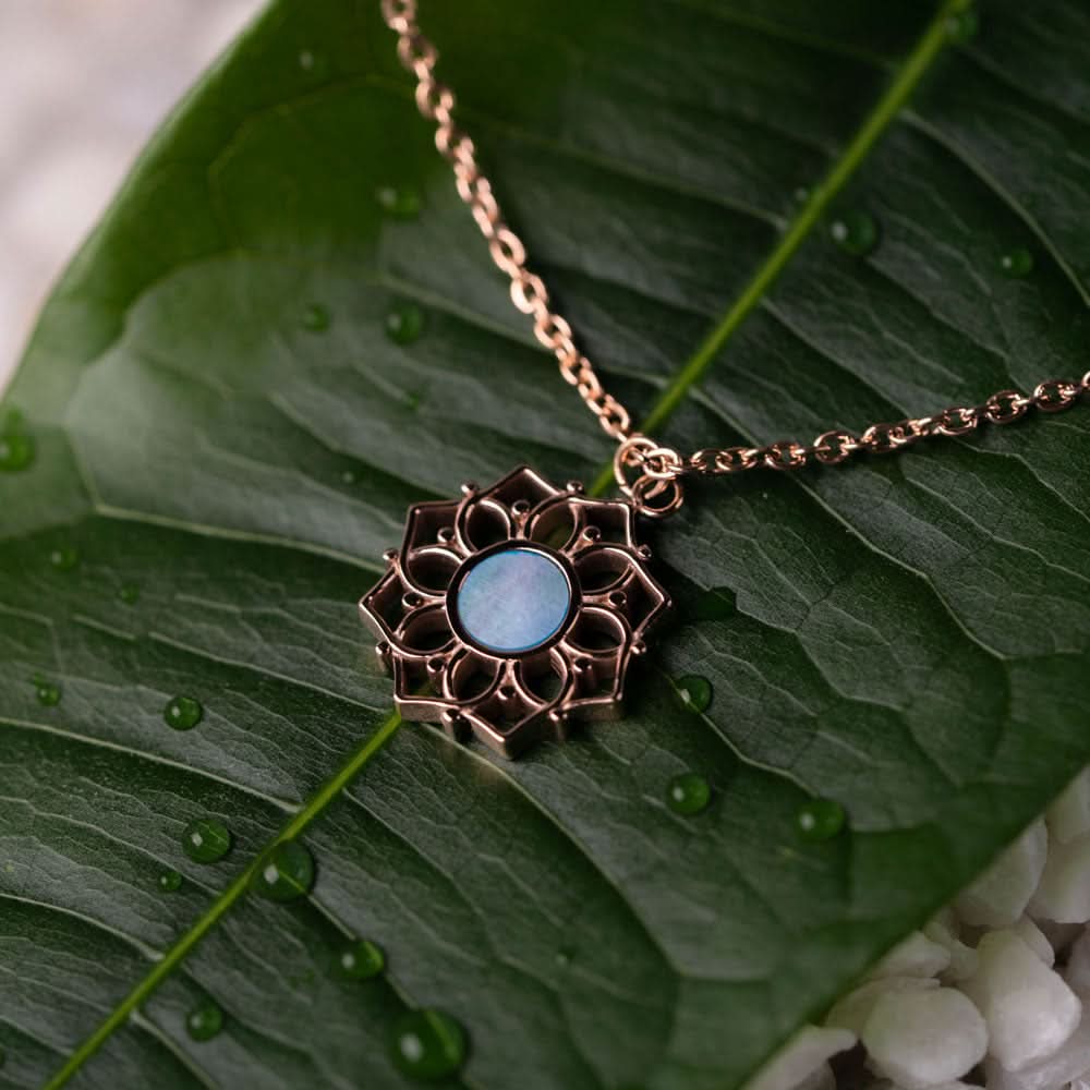 Halsband med runt hänge i blå pärlemor och blomformad metallram
