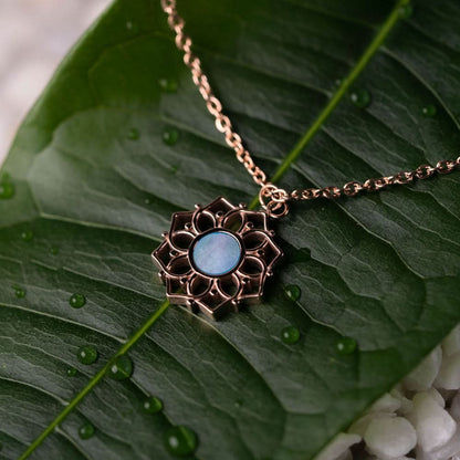 Halsband med runt hänge i blå pärlemor och blomformad metallram