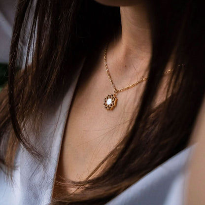 "Guldpläterat halsband runt halsen med rund pärlemorsten i blommigt hänge"