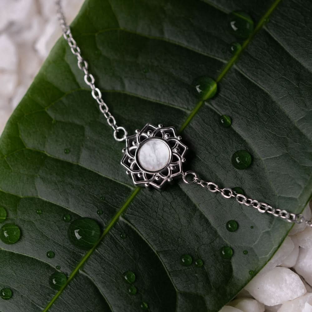 Armband med silverfärgad kedja och runt hänge i pärlemor med dekorerad kant