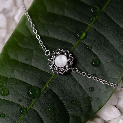 Armband med silverfärgad kedja och runt hänge i pärlemor med dekorerad kant