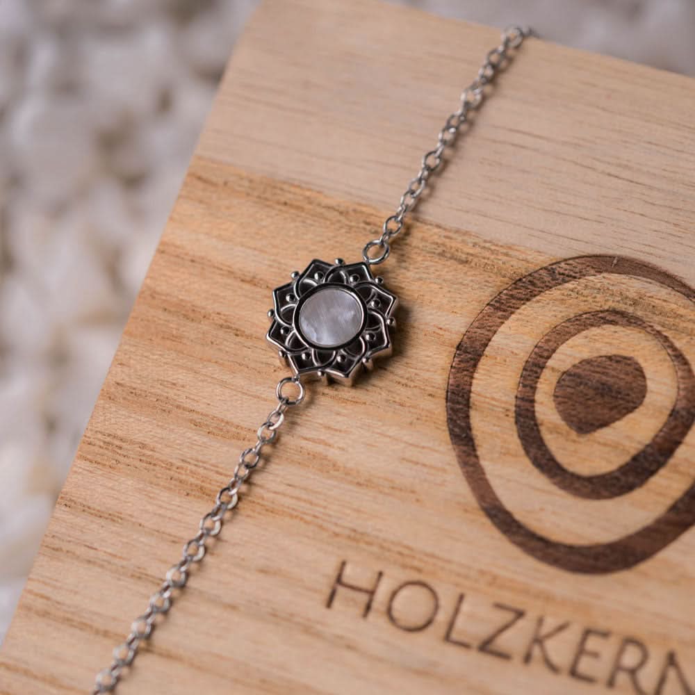 Armband med silverfärgat kedja och runt pärlemorhänge i detaljerat infattning