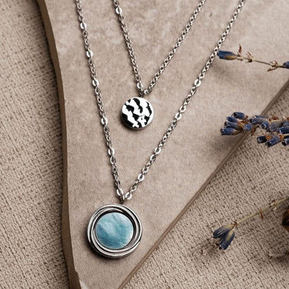 Lagerhalsband i silver med runt pärlemorhänge och en liten svartvit berlock