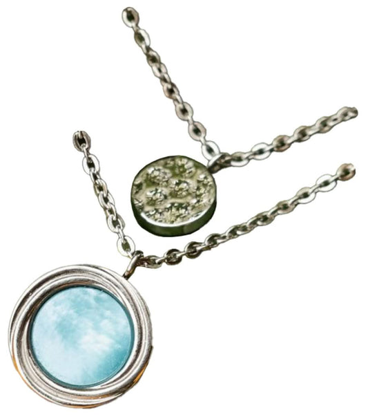 Lagerhalsband i silver med runt pärlemorhänge och liten fläckig berlock