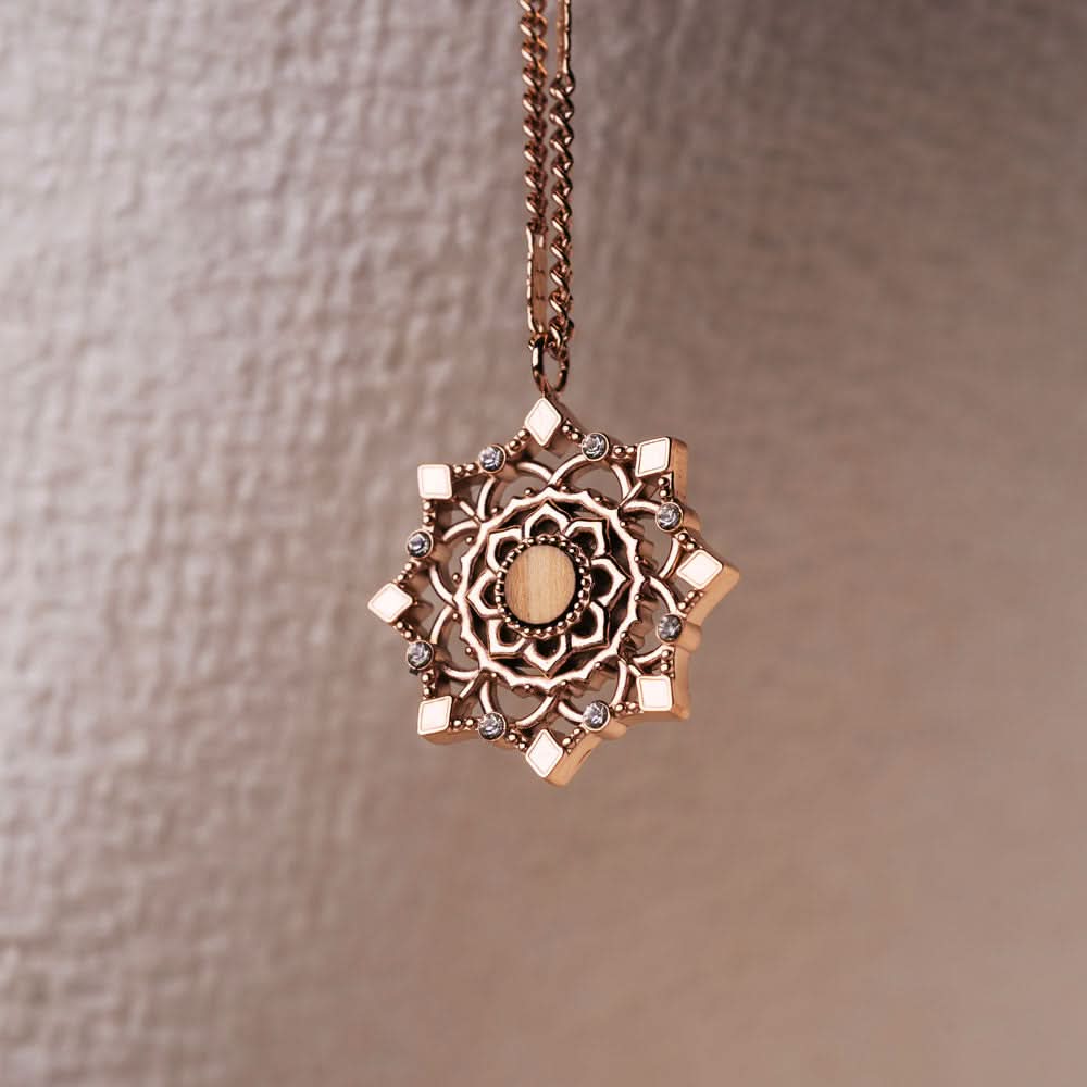 Halsband med guldfärgad kedja och runt hänge med dekorativa ornament