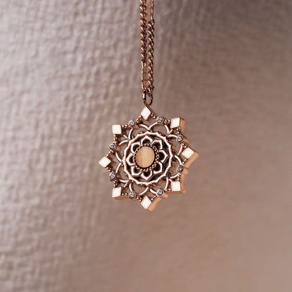 Halsband med guldfärgad kedja och runt hänge med dekorativa ornament