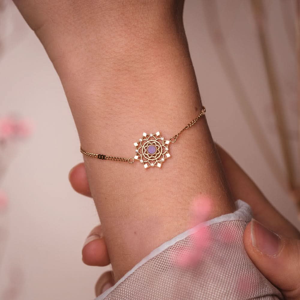Armband runt handleden med filigran snöflingeberlock i guldfärg och lila sten