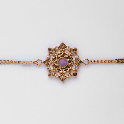 Armband med guldfärgad kedjelänk och snöflingeberlock med lila sten