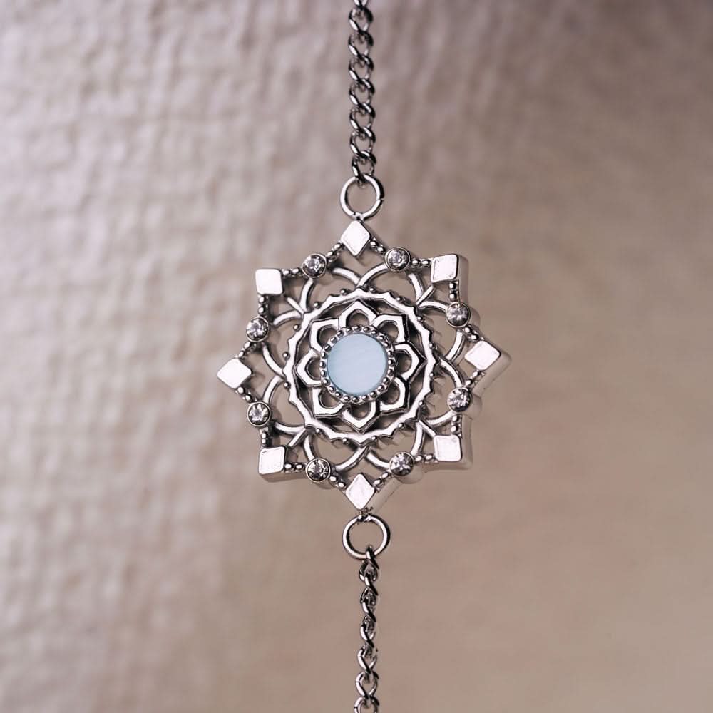 Armbandberlock med rund, blåskimrande yta, dekorerad med filigrana element