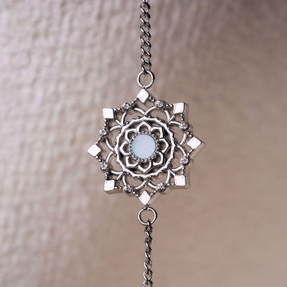 Armbandberlock med rund, blåskimrande yta, dekorerad med filigrana element