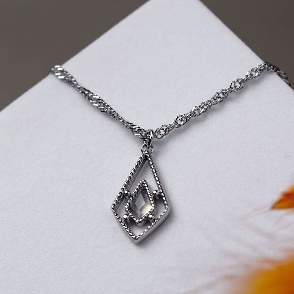 Silverfärgat halsband med fyrkantigt hänge och ljus sten, detaljvy