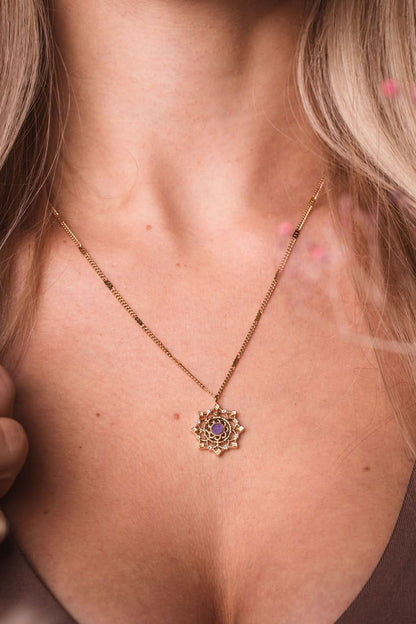 Guldpläterat halsband med litet ornamenthänge och lila sten i cirkelform