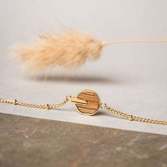 Armband med rund träskiva, guldfärgat kedja och ljus fluffig detalj