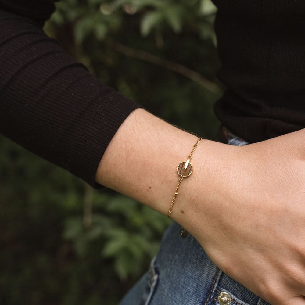 Armband runt handleden med guldfärgad kedja och runt träpärla