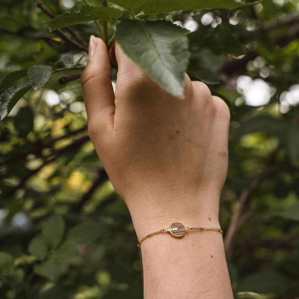 Armband runt handleden med guldfärgad kedja och rund träskiva