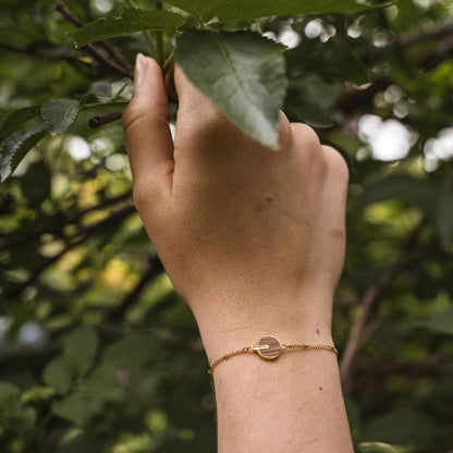 Armband runt handleden med guldfärgad kedja och rund träskiva