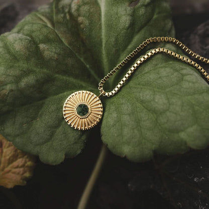 Guldigt halsband med rund berlock och grön sten