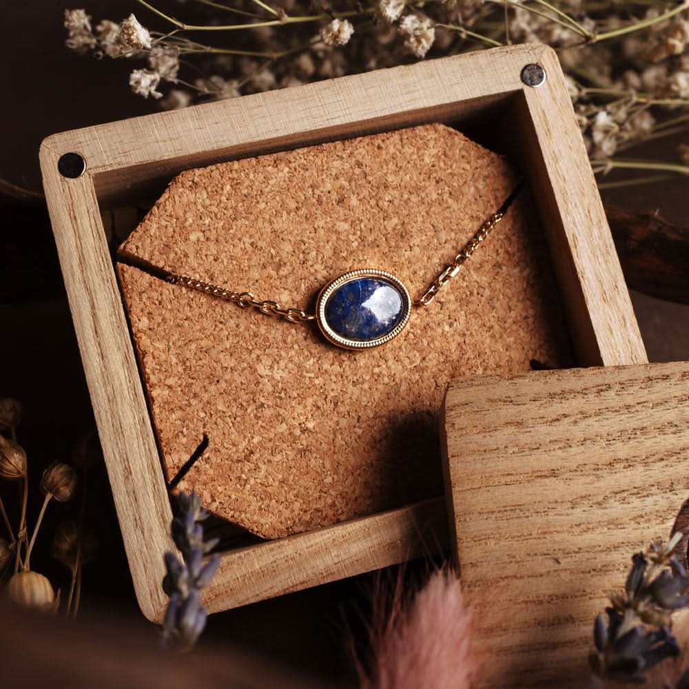 Ovalt hänge på guldfärgat armband med blå cabochon