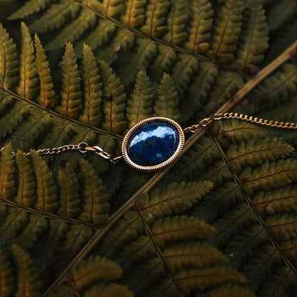 Guldpläterat armband med oval blå cabochon-berlock, silverfärgad infattning
