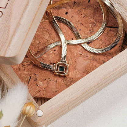 Guldpläterat ormliknande halsband med fyrkantigt hänge och turkos sten, närbild
