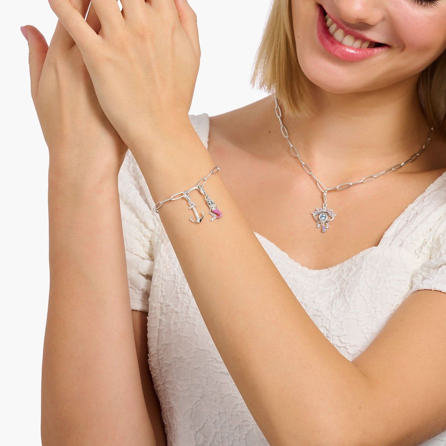 Silverfärgad ankarcharm på armband med små stenar, buren på handleden